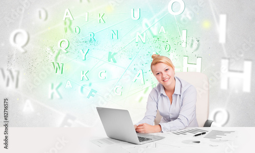 Business woman at desk with green word cloud