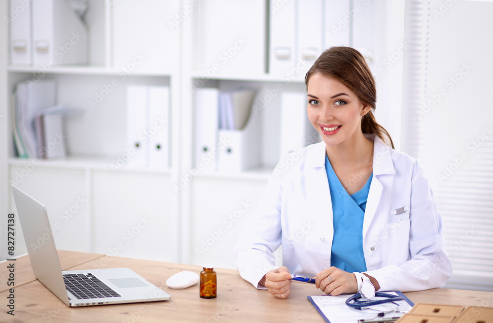 Female doctor sitting on the desk and working a laptop Female doctor sitting on the desk and working a laptop