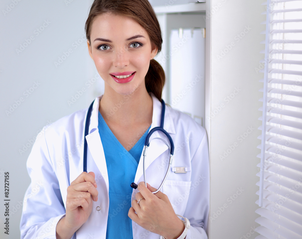 Woman doctor is standing near window with crossed arms,isolated Woman doctor is standing near window with crossed arms,isolated
