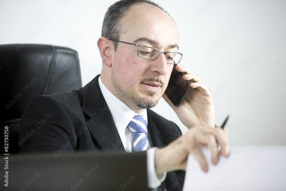 Portrait of a businessman talking on mobile phone in office Portrait of a businessman talking on mobile phone in office