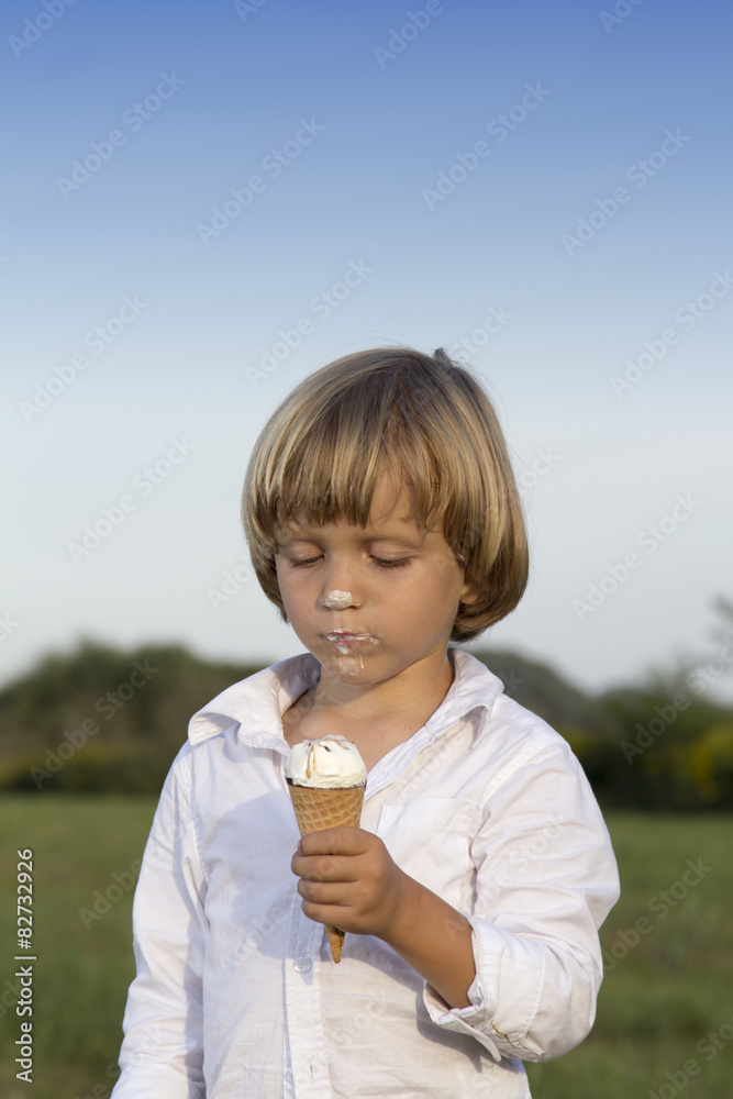 Young cute boy eating a tasty ice cream in the park