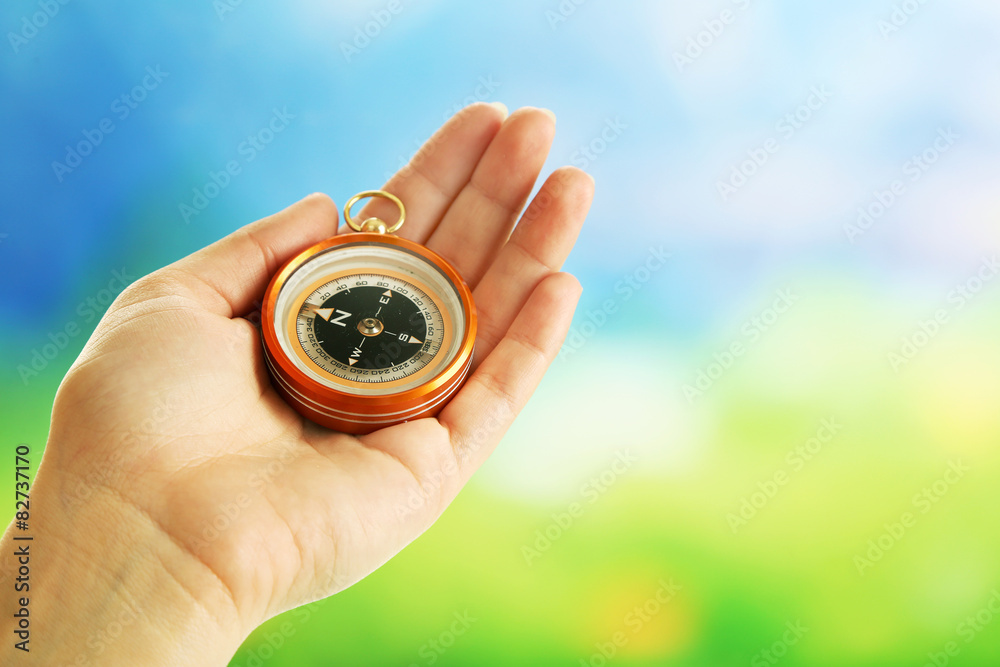 Female hand with compass on bright blurred background