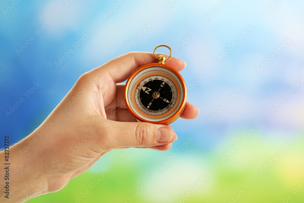 Female hand with compass on bright blurred background Female hand with compass on bright blurred background