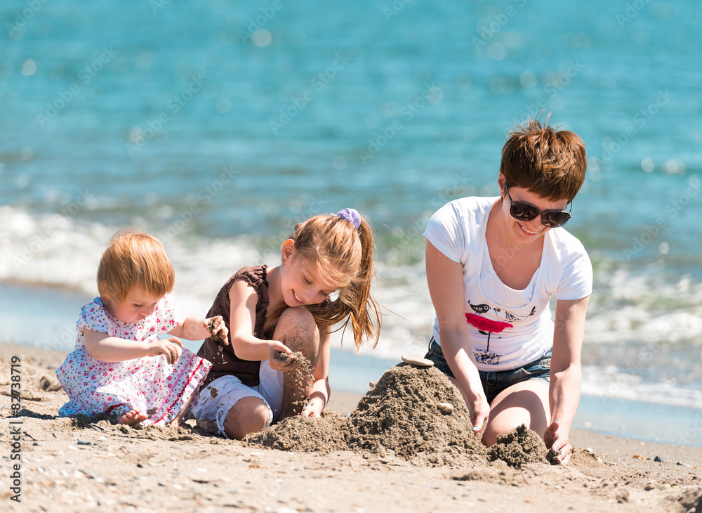 mother and daughters playing in the sand mother and daughters playing in the sand
