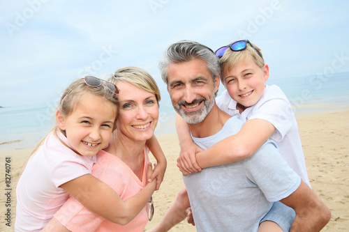 Parents giving piggyback ride to children at the beach