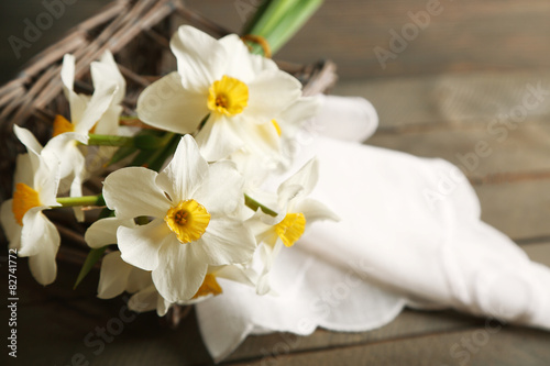 Fresh narcissus with wicker basket on wooden background