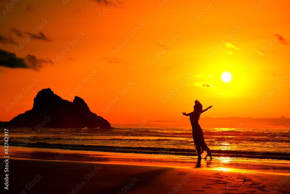 young woman silhouette on the beach in summer sunset light