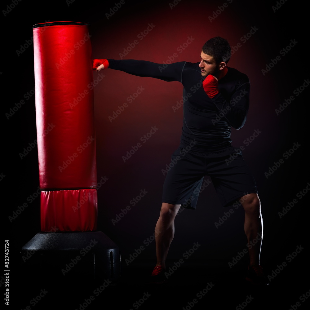 young man standing exercising with  boxing bag in studio