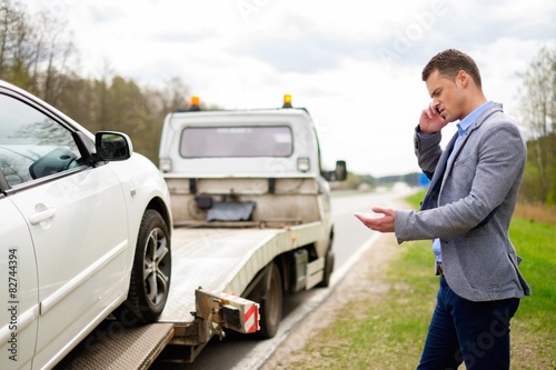 Canvas Print Man calling while tow truck picking up his broken car