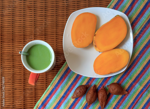 cup of green tea with tropical fruits on a glass surface photo