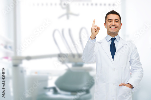 smiling male dentist pointing finger up