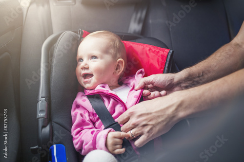Little baby girl in a car in a child seat photo