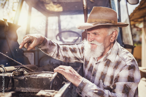 Senior man at the farm repairing an old tractor