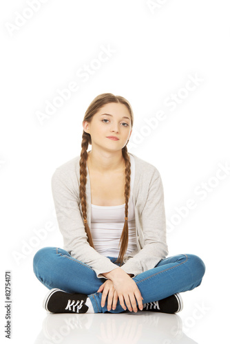 Happy teen woman sitting cross legged.