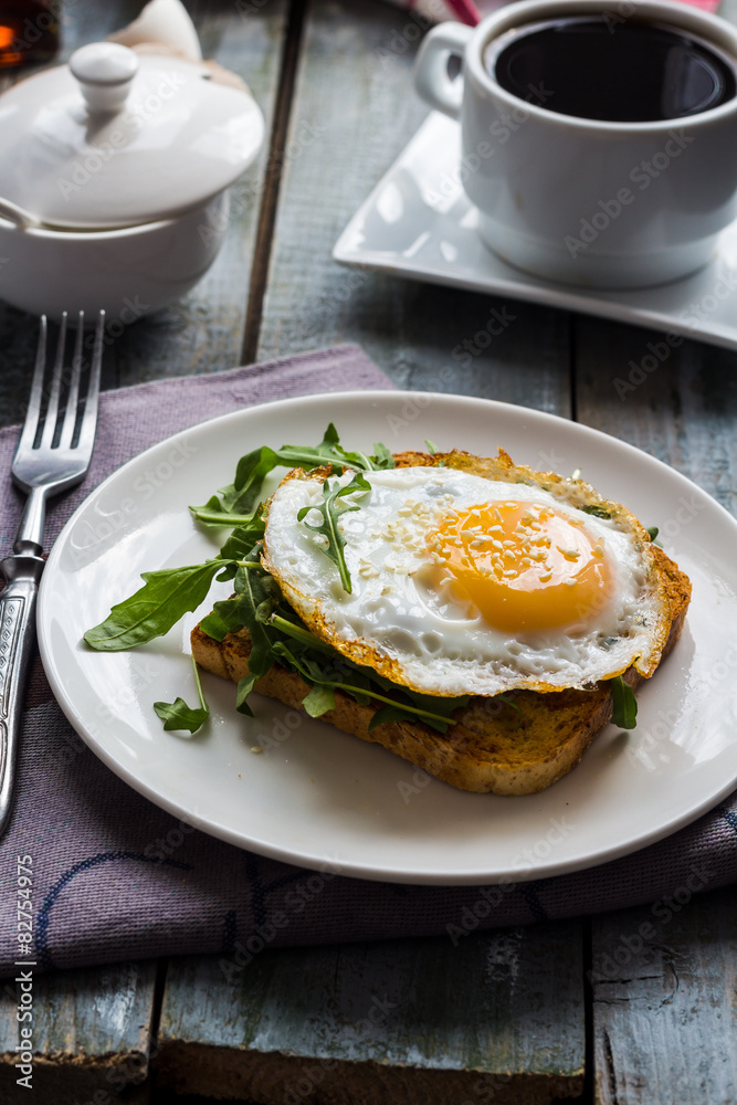 crispy toast with a fried egg and fresh arugula, a cup of coffee crispy toast with a fried egg and fresh arugula, a cup of coffee