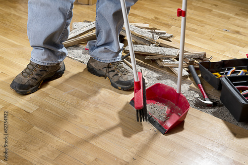 An unrecognizable person with a broom sweeping floor.