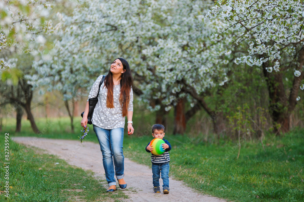 Fototapeta premium Mother and son walking along the blossoming spring garden