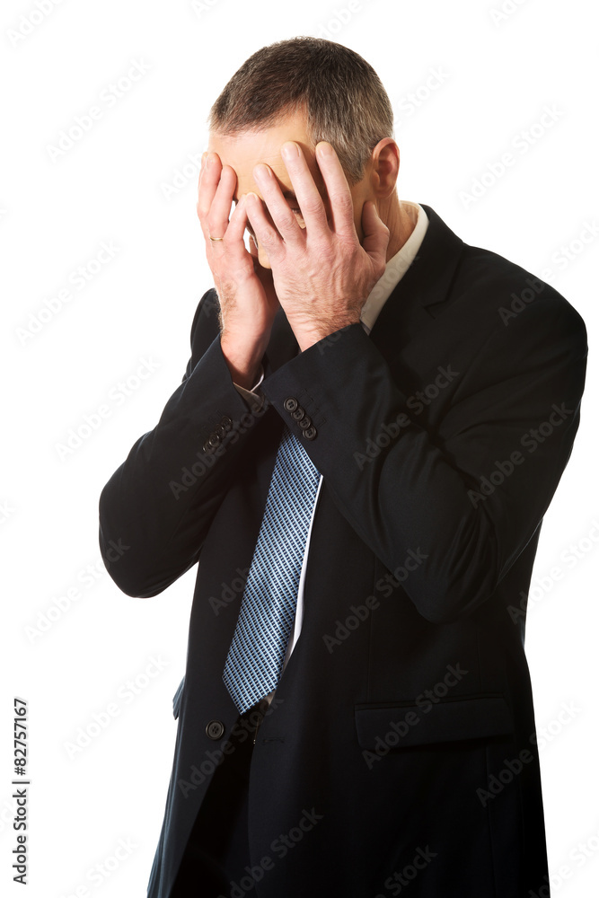 Stressed businessman covering his face with hands Stressed businessman covering his face with hands