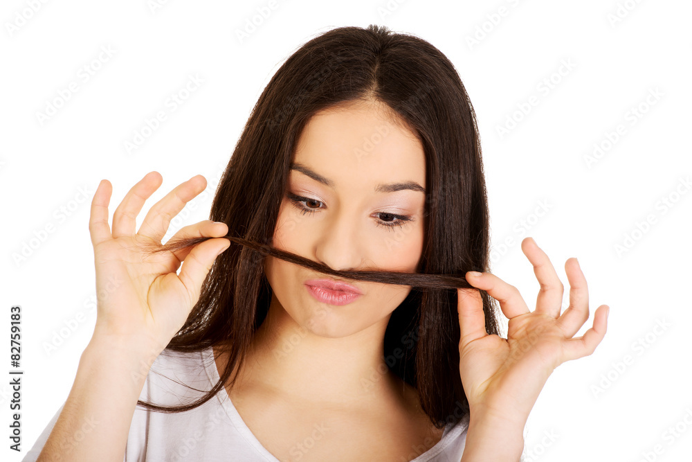 Teen woman putting hair like moustache. Teen woman putting hair like moustache.