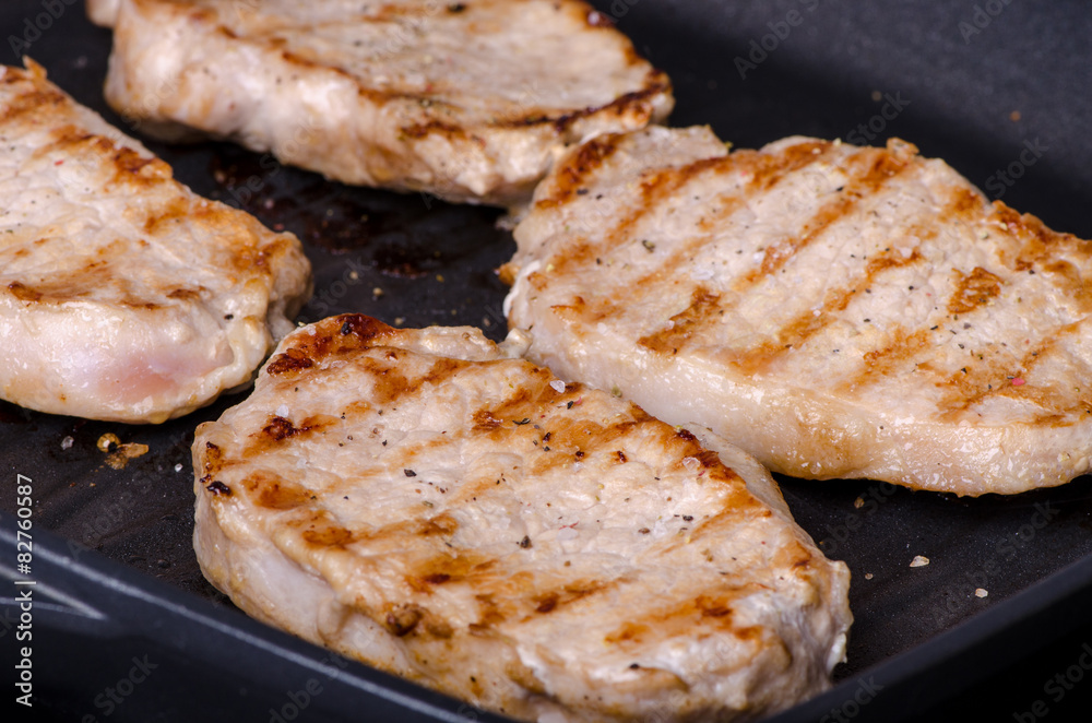 grilled pork steak in a frying pan during cooking grilled pork steak in a frying pan during cooking