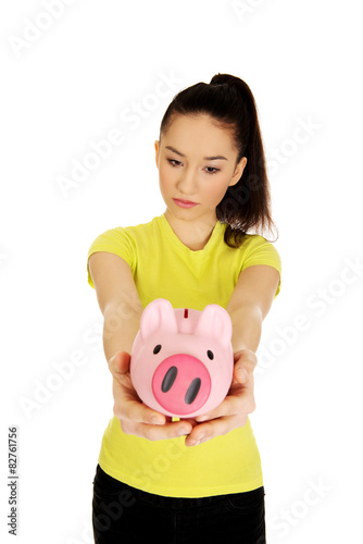 Unhappy woman holding piggybank.