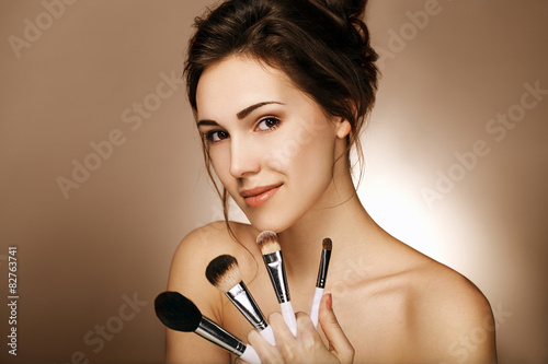 Close-up portrait of beautiful girl with makeup brushes.Applying