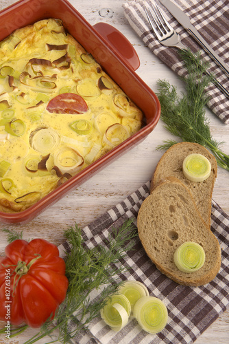 Omelette with tomato and leek baked in red pan.