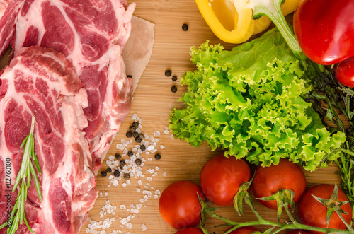 Raw meat with vegetables and spices on wooden background