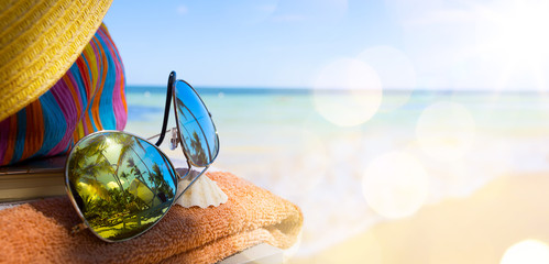 Straw hat, bag and sun glasses  on a tropical beach