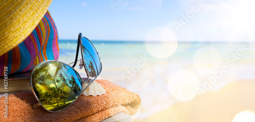 Straw hat, bag and sun glasses  on a tropical beach