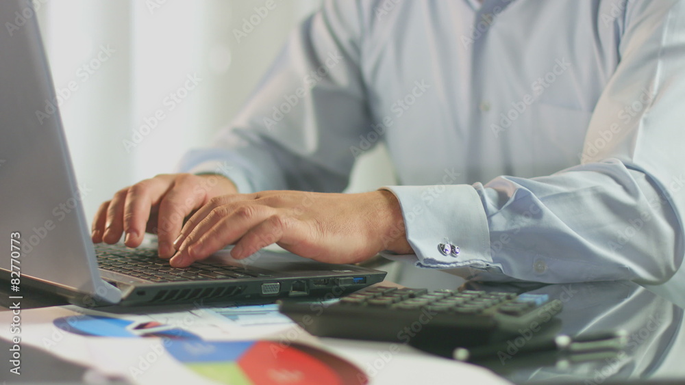 Businessman working on laptop, calculating data for tax report 