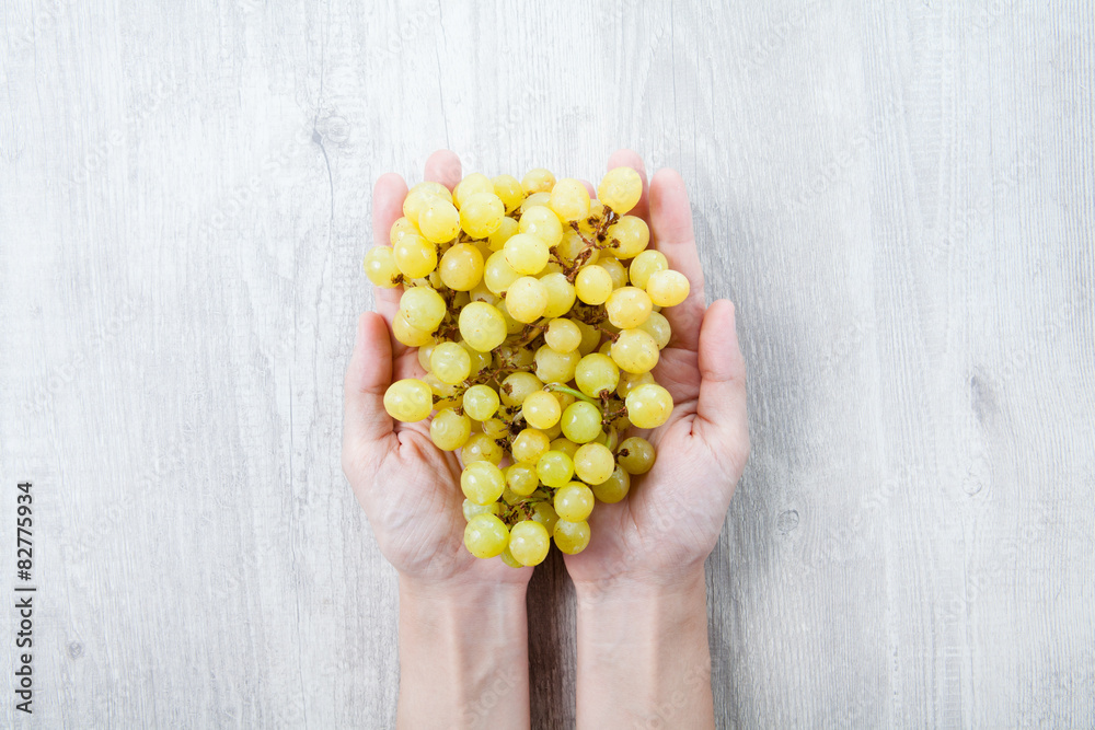 Hand with freshly grapes on a wooden table