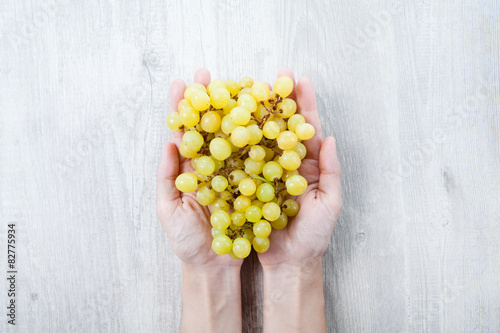 Obraz na płótnie Hand with freshly grapes on a wooden table w salonie