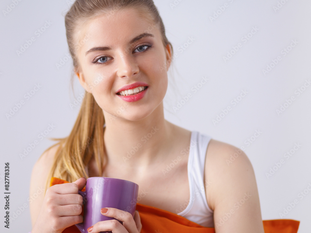 Young woman sitting with pillow and holding a cup of tea Young woman sitting with pillow and holding a cup of tea