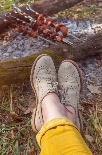 Recreation scene: woman feet in light brogues by camp fire