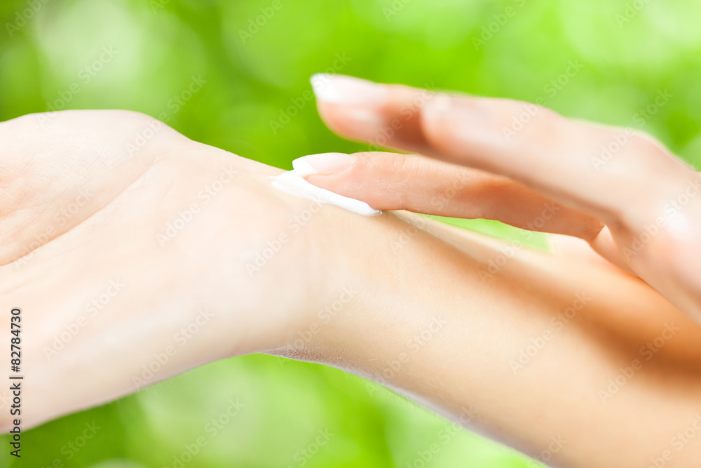 Naklejka premium Young woman applying skin cream on her hand