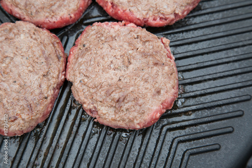 Part cooked burgers on a metal griddle