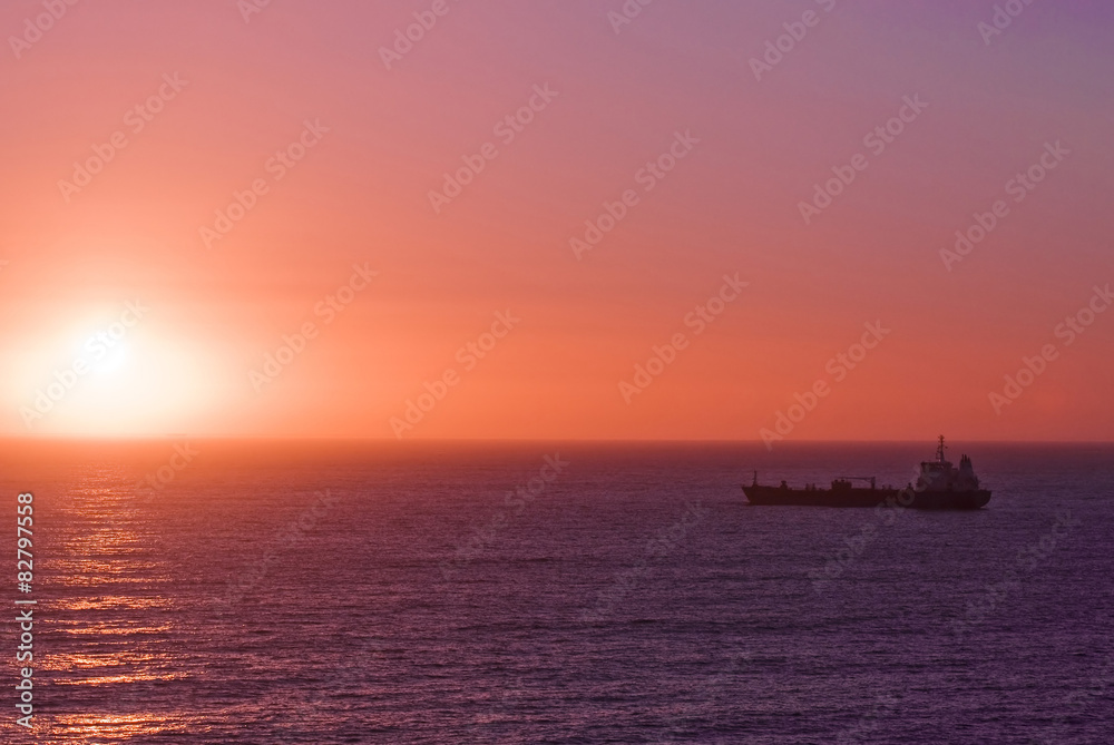 Silhouette of the cargo ship over the sunrise