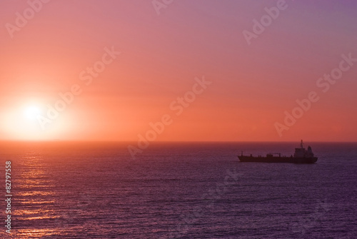 Silhouette of the cargo ship over the sunrise © donvictori0