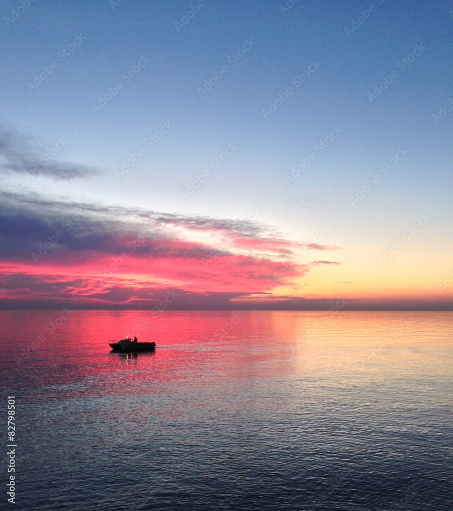 lonely fisher in the sea at sunset