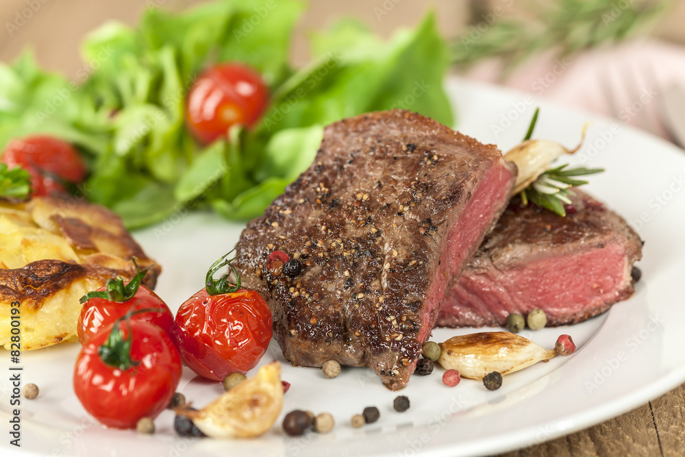 Filetsteak medium auf Teller mit Tomate und Kartoffelgratin Filetsteak medium auf Teller mit Tomate und Kartoffelgratin