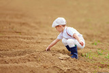 cute little farmer spuding the soil on spring field