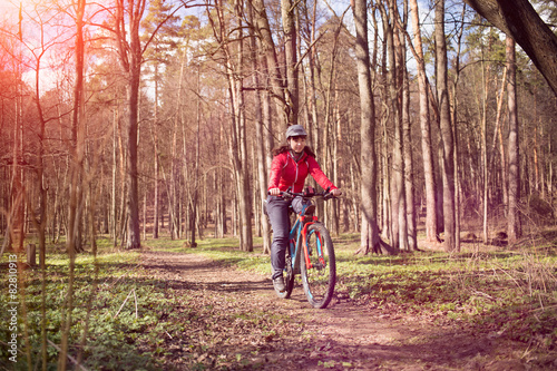 Young woman riding a bicycle through forest