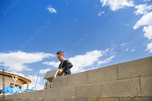 Cuadro en lienzo Bricklayer putting down another row of bricks in site