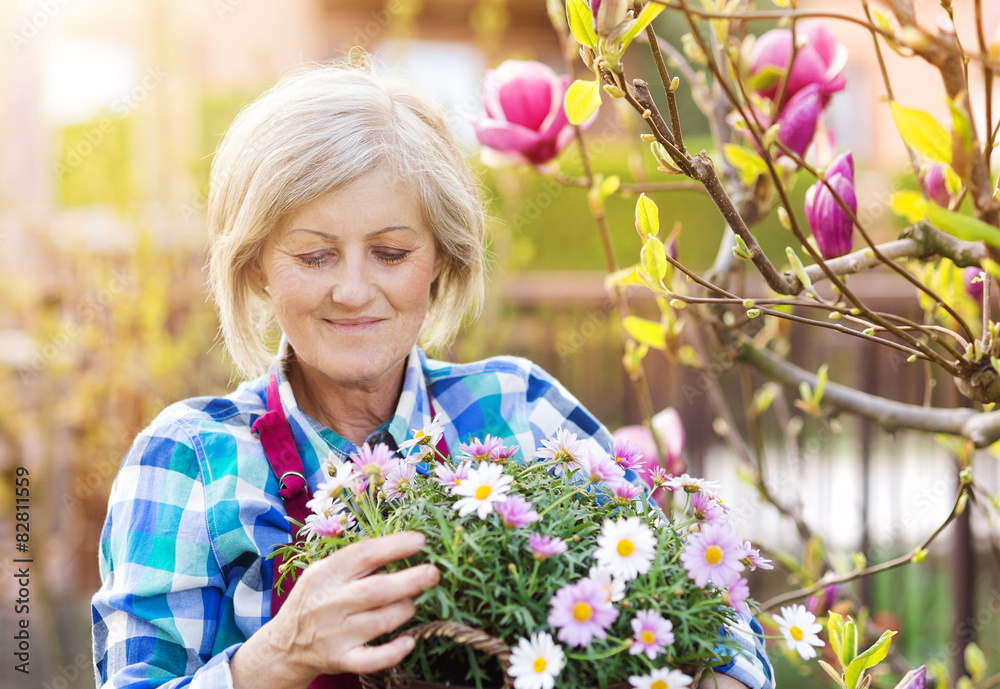 Beautiful senior woman planting flowers in her garden Beautiful senior woman planting flowers in her garden