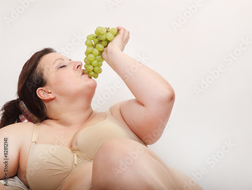 Overweight woman eating fresh sweet grape.