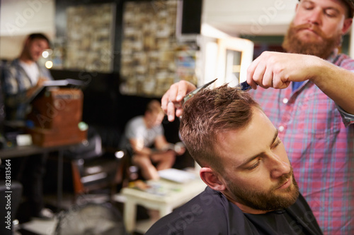 Male Barber Giving Client Haircut In Shop