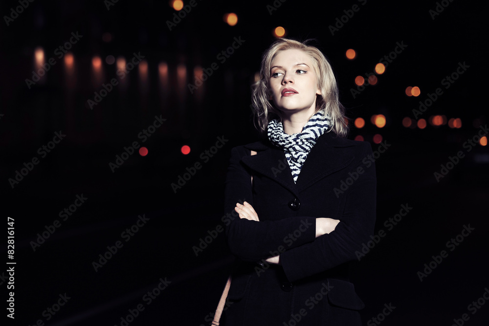 Young blond fashion woman walking on a night city street