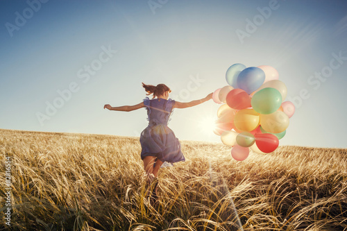 Beautiful woman with colorful balloons outside.