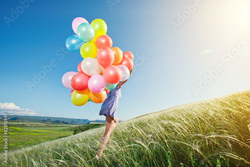 Beautiful woman with colorful balloons outside.